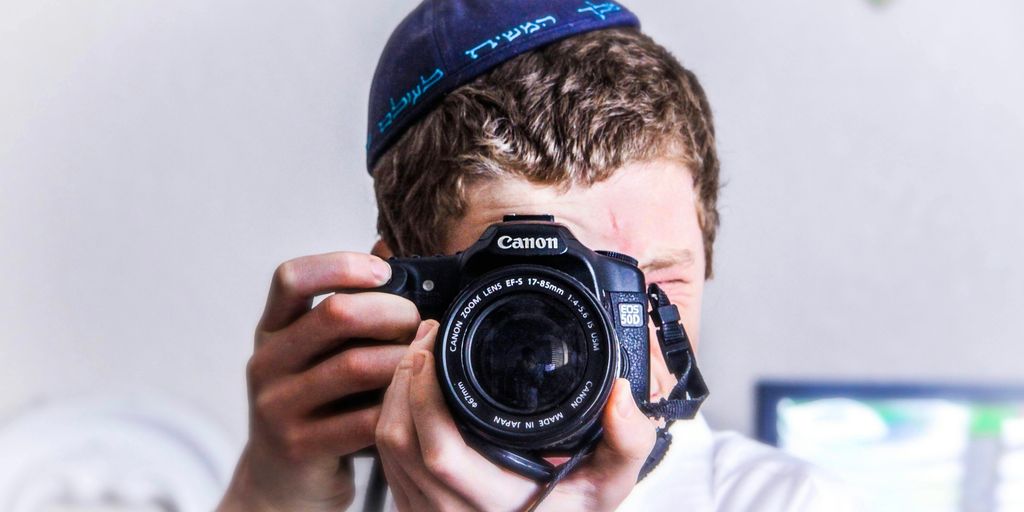 man in blue knit cap holding black and silver nikon dslr camera