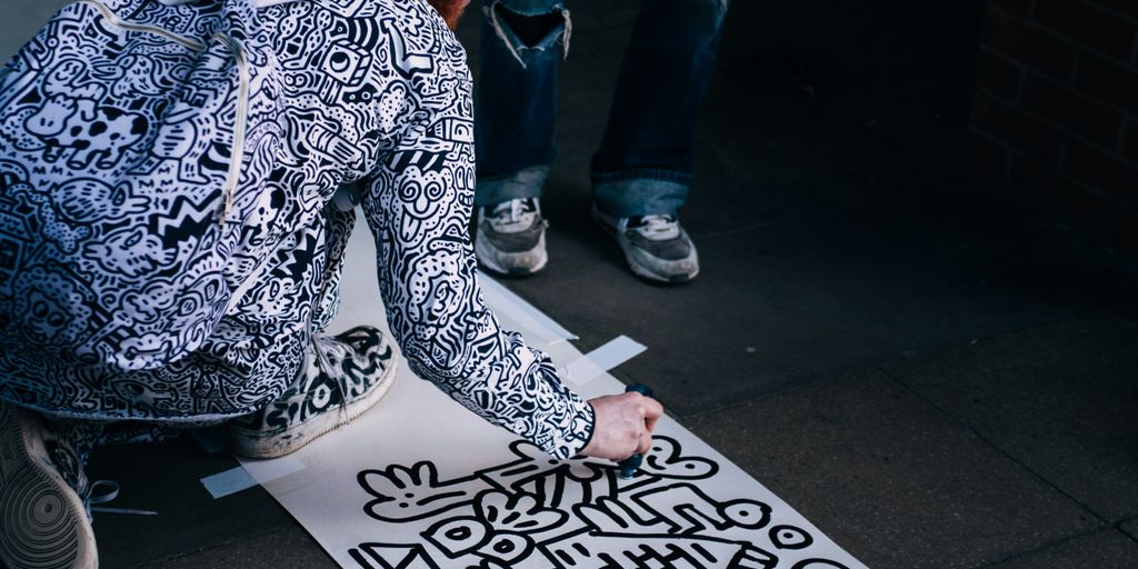 man drawing on white paper while kneeling at daytime